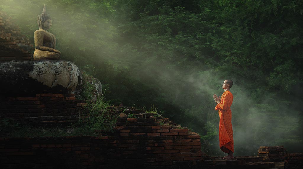Templos de Angkor: monge diante de um buda no Templo Bayon