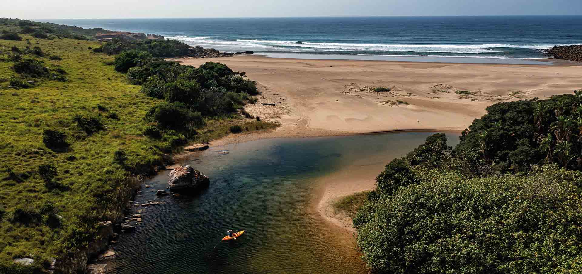 Vista aérea do GweGwe Beach Lodge integrado à Reserva de Mkambati, com falésias, rios cristalinos e Oceano Índico ao fundo, na Wild Coast da África do Sul.