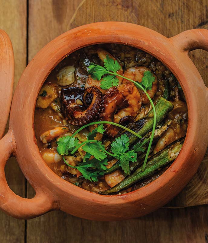 Close do arroz caldoso com mariscos, camarão e polvo, servido com quiabo grelhado.
