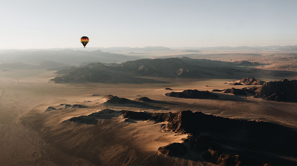 Balão da Namib Sky Adventures sobre o Deserto do Namibe ao amanhecer.
