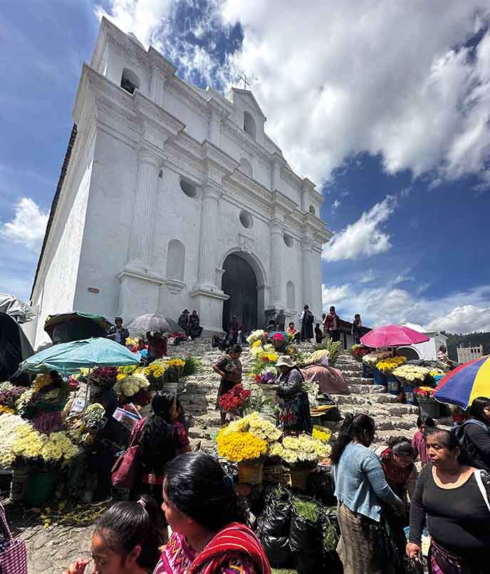 Escadaria da igreja de Chichicastenango tomada por flores e vendedores maias na Guatemala, parada vibrante em roteiro de viagem cultural