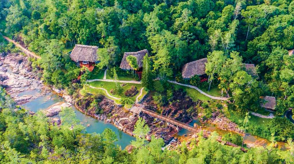 Vista aérea do Blancaneaux Lodge em Belize, bangalôs na floresta às margens do rio, base perfeita de onde ficar para explorar Caracol