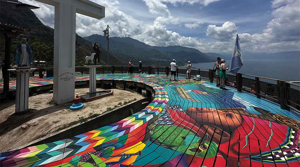 Mirante colorido em San Juan La Laguna com cruz branca e vista para o Lago Atitlán, na Guatemala, ponto cênico em roteiro de viagem
