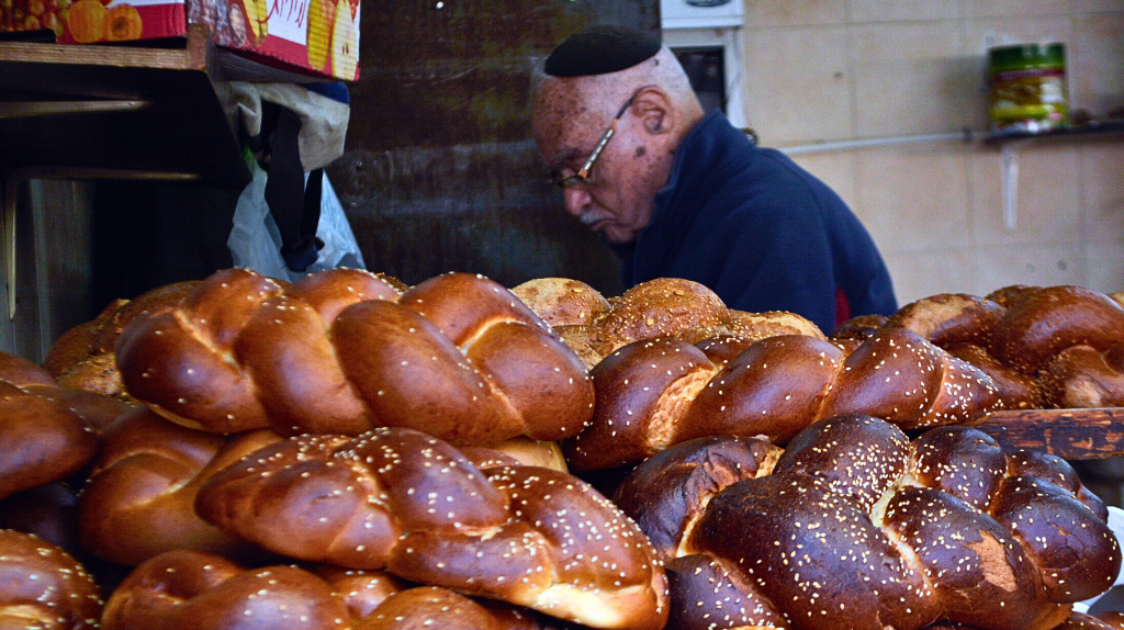 Baker_with_challah_at_Mehane_Yehuda_Market ProtoplasmaKid, CC BY-SA 4.0 <https-:creativecommons.org:licenses:by-sa:4.0>