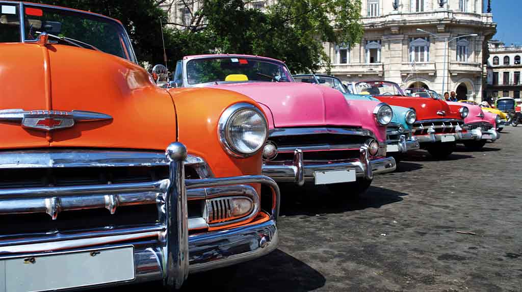 Fileira de carros antigos coloridos no centro de Havana, Cuba, ícone das viagens clássicas e dos passeios turísticos pela cidade
