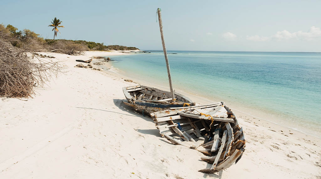 Carcaças de barcos de madeira antigos repousando nas areias brancas da Ilha de Santa Carolina, parte histórica do arquipélago.