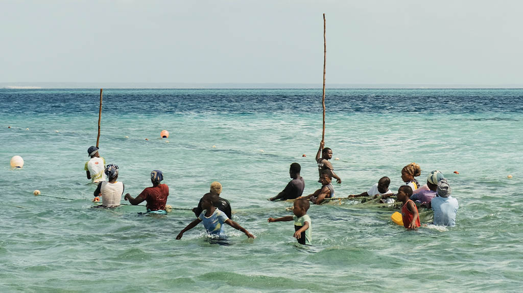 Grupo de moradores locais realizando a pesca de arrasto tradicional com água na cintura na costa da Ilha de Benguerra.