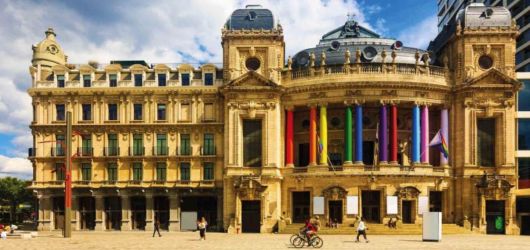 Teatro histórico com colunas nas cores do orgulho LGBTQIA+ em Antuérpia, Bélgica, cenário imperdível em roteiro de viagem cultural