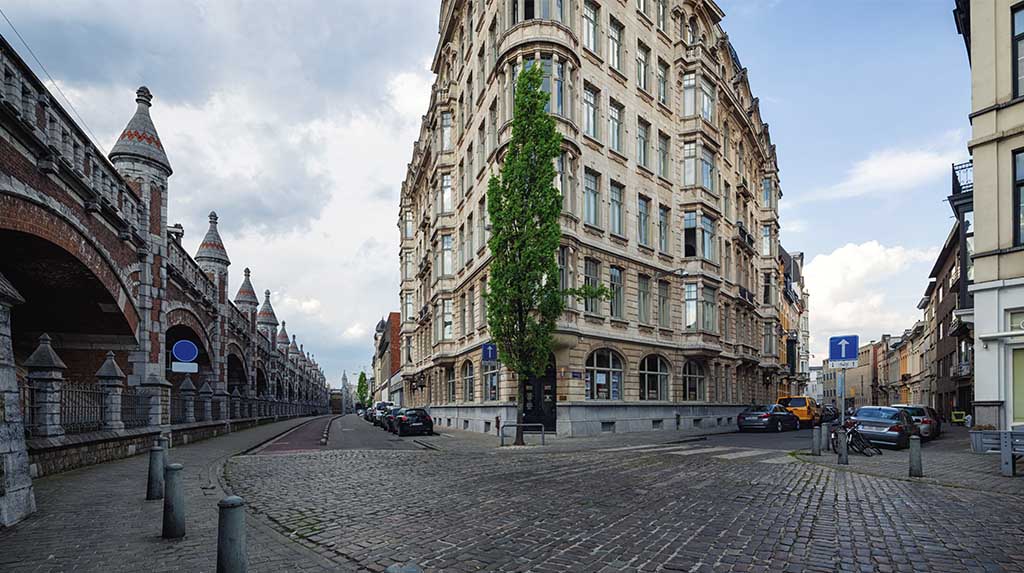 Rua de paralelepípedos entre viaduto antigo e prédio histórico em Antuérpia, Bélgica, dica de passeio a pé em roteiro de viagem urbana