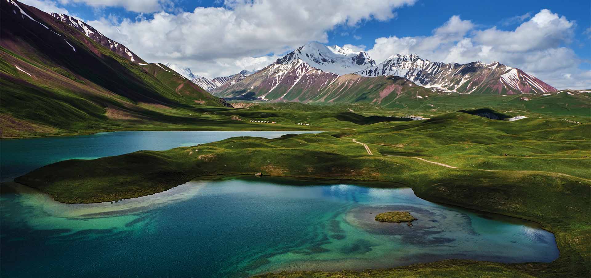 Paisagem alpina do Quirguistão com lago de águas turquesa, colinas verdes e cadeia de montanhas nevadas no verão, região de Song-Kul, Ásia Central