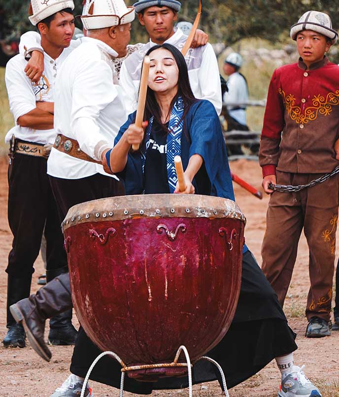Participantes do Salburun Birds of Prey Festival no Quirguistão, com tambores tradicionais e trajes típicos da cultura nômade.