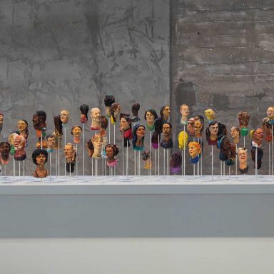 Instalação artística com múltiplos bustos coloridos e de etnias diversas, representando a condição humana e a diversidade. Arte contemporânea Fenix Museum.
