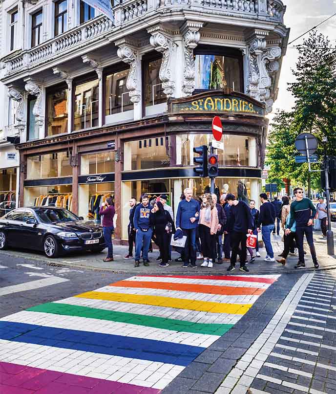 Faixa de pedestres arco-íris em Antuérpia, Bélgica, diante de prédio histórico, símbolo da cena LGBTQIA+ em roteiro de viagem urbana