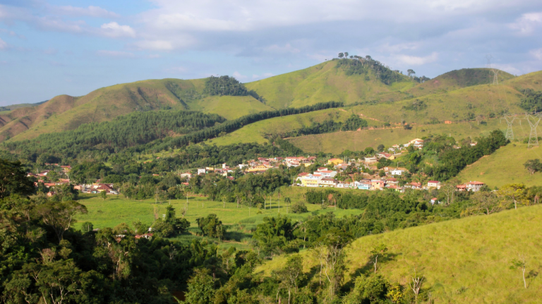 Vista panorâmica de São José do Barreiro cercada por colinas verdes no interior de São Paulo, com casas baixas no vale e céu parcialmente nublado