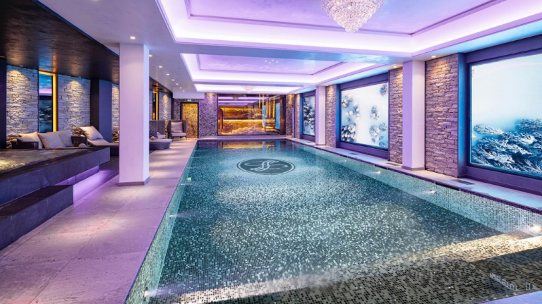 Piscina coberta do Spa Clarins no Hôtel Le Lana, em Courchevel 1850, com iluminação suave e paredes em pedra — relax pós-esqui Piscina coberta do Spa Clarins no Hôtel Le Lana