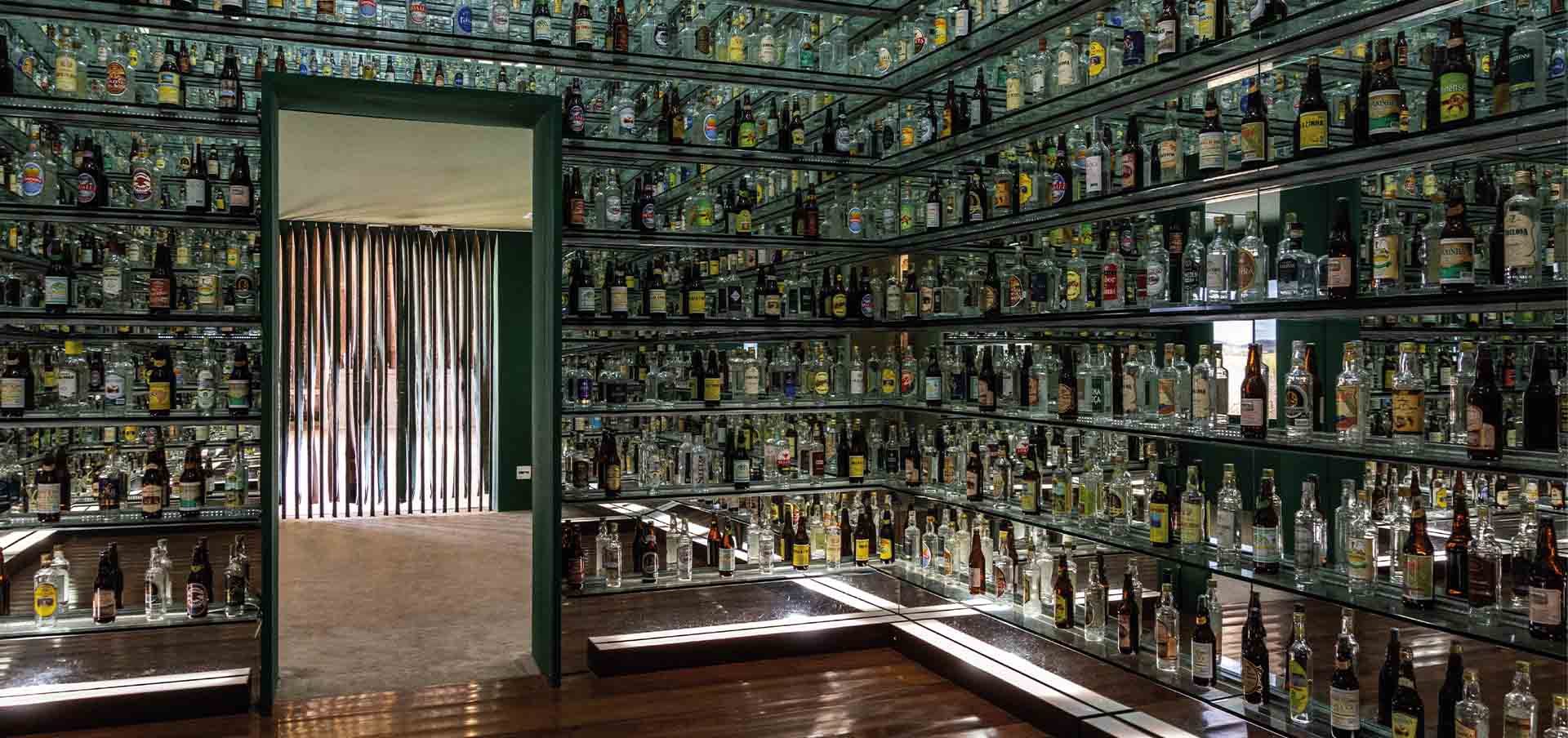 Sala com garrafas e rótulos de cachaça de alambique em Minas Gerais, no Sudeste do Brasil, em roteiro cultural sobre tradição, patrimônio e história mineira.