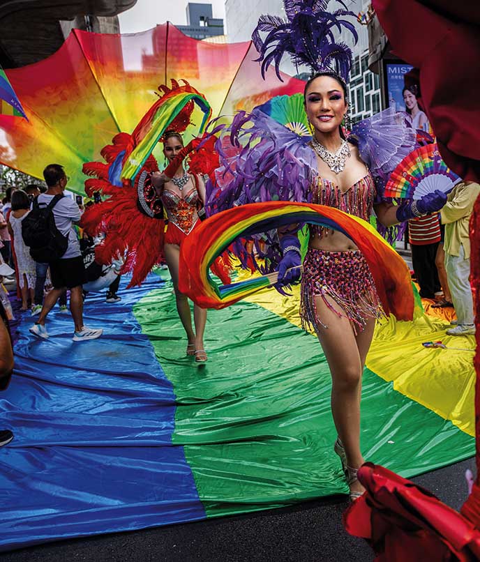 Performer com fantasia colorida participa de desfile do Orgulho LGBTQIA+, em cena que une cultura queer, festa e visibilidade pública.
