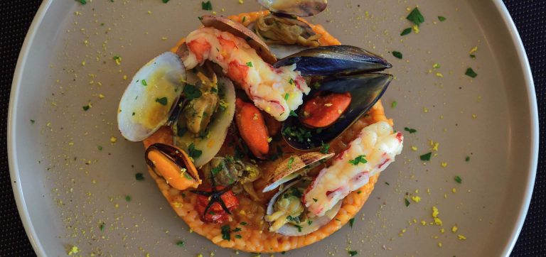 Prato de arroz cremoso com frutos do mar, camarões, mexilhões e vôngoles, representando a gastronomia do norte da Espanha, entre Cantábria, Astúrias e litoral atlântico.
