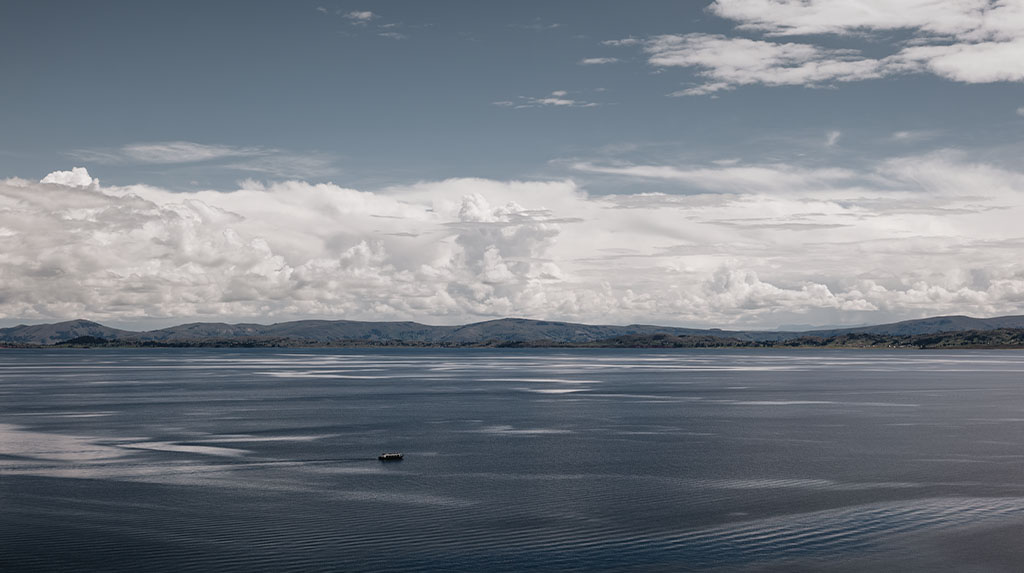 Vista ampla do Lago Titicaca, na região de Puno, com embarcação ao fundo