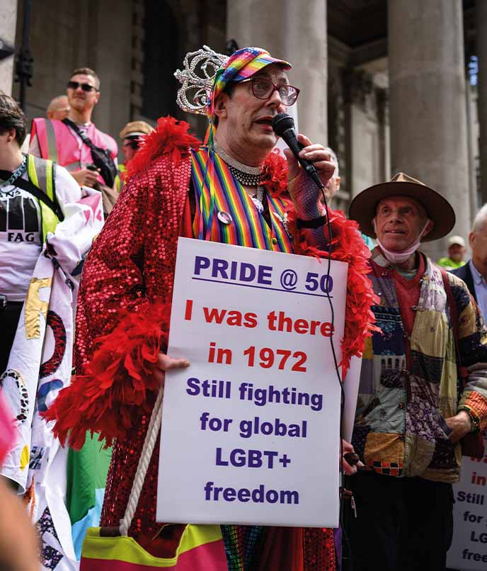 Participante segura cartaz em manifestação do Orgulho LGBTQIA+, reforçando a dimensão política das Paradas pelo mundo.
